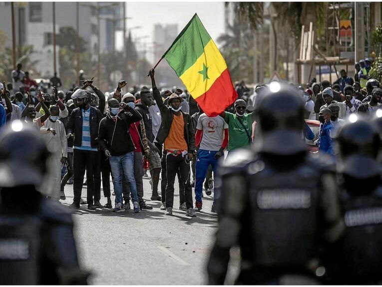 Manifestant brandissant le drapeau du Sénégal dans une rue de Dakar