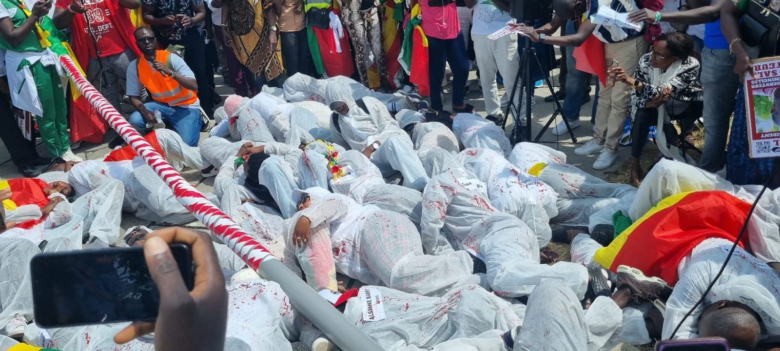 Hommage symbolique aux victimes, manifestants allongés vêtus de blanc lors d'un rassemblement